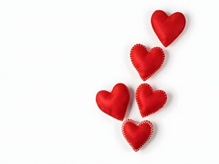 Fototapeta premium Red felt heart shapes scattered on white background for love, Valentine, and romance designs