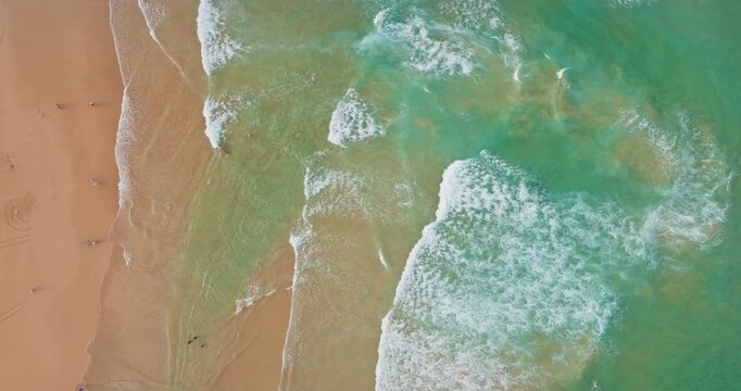 Sydney Manly Beach golden sand, turquoise water and white foamy waves. An idyllic scene representing people enjoying summer vacation and relaxation. Nature travel background. Aerial top-down view