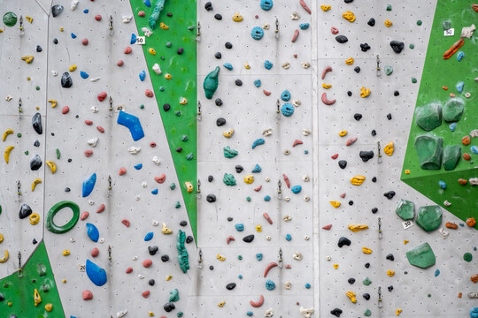 Eine riesige Kletterwand mit bunten Griffen und Tritten in einer Kletterhalle. Die moderne Trainingswand bietet abwechslungsreiche Routen f&uuml;r Klettersportler, Boulderer und Aktivurlauber.