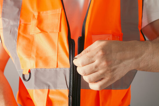 Man in a reflective vest on a gray background. Close-up.