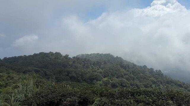 Panoramic view of green tropical mountain hills and rolling white clouds
