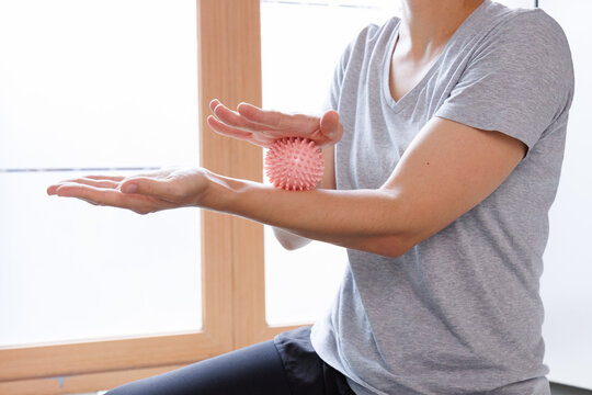 Hands using a spiky massage ball for self massage and muscle relaxation, relieving tension and supporting hand, wrist and forearm recovery after exercise.