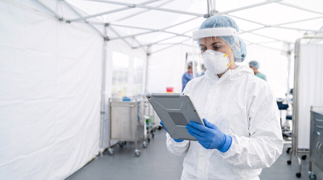 Professionnelle en combinaison de protection utilisant une tablette dans une zone m&eacute;dicale