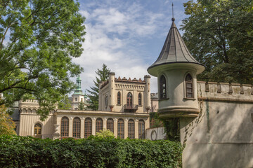 Zabytkowy zamek z charakterystyczną wieżyczką i neogotycką architekturą otoczony zielenią drzew i krzewów. © Henryk Guziak