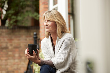 Fototapeta premium Coffee, relax and thinking with woman on balcony for morning contemplation, ideas or vision. Break, drink and happy with mature person outdoor on terrace of apartment for memory, nostalgia or view