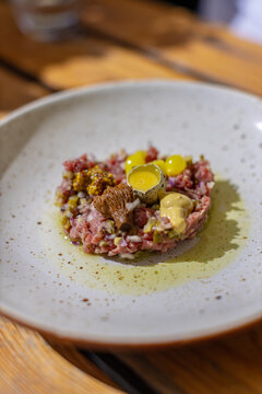 Gourmet beef tartare with raw quail egg yolk and mustard in restaurant setting