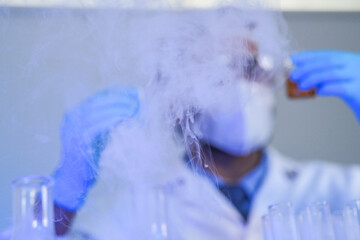 Scientists in lab coats and masks examine samples with a microscope and test tubes in a modern...
