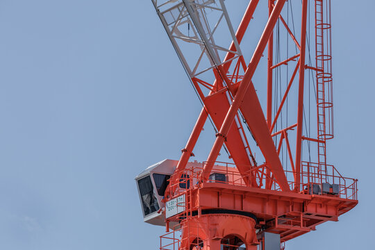 Luffing jib tower crane cabin and slewing platform set against a clear blue sky in Japan.