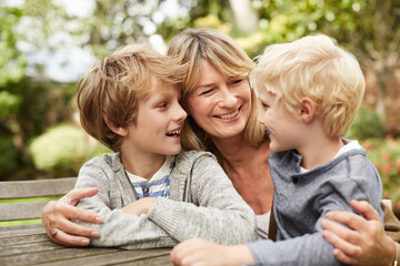 Fototapeta premium Smile, grandmother and kids in nature with hug, love and bonding together on holiday. Happy, mature woman and children outdoor with embrace, family affection and parental support on getaway vacation