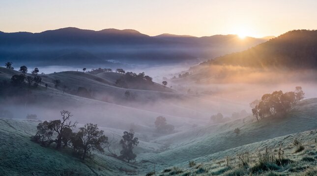 Vast mountain valley at sunrise with mist layers and soft golden light.