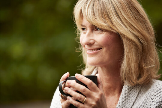 Thinking, coffee and mature woman outdoor with smile, daydreaming and nostalgia in calm mindset. Space, reflection and person in backyard with mug, happy flashback and insight in peaceful perspective
