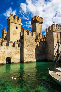 Sunlit facade of the Rocca Scaligera of Sirmione from the port, a medieval fortress and sole access point to the historic center of the town