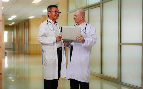 Medical Consultation: Two seasoned doctors, clad in lab coats and stethoscopes, intently examine a laptop screen, their expressions suggesting a deep discussion about patient care.