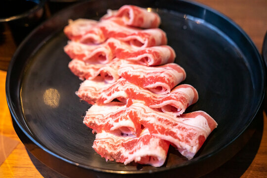 A hotpot meat platter presents thinly sliced beef, pork, and chicken arranged neatly on a serving plate. Close-up compositions emphasize beef marbling, pork color, and the natural fiber patterns of ch
