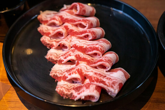 A hotpot meat platter presents thinly sliced beef, pork, and chicken arranged neatly on a serving plate. Close-up compositions emphasize beef marbling, pork color, and the natural fiber patterns of ch