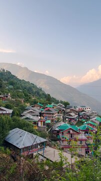4K Vertical shot of an Himalayan village with old kath kuni architecture homes on a mountain during the sunset at Peej village near Kullu in Himachal Pradesh, India. Old Himalayan village background.