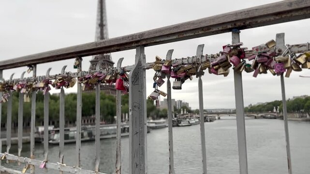 Footage of love locks attached to a bridge railing over the Seine River in Paris, France, with the Eiffel Tower visible in the background.