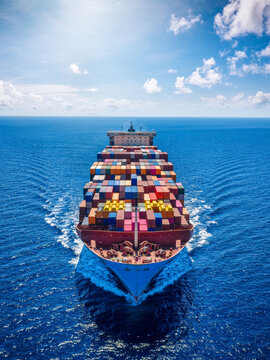 Aerial front view of a large container cargo carrier ship cruising with speed over the ocean as a industrial transport concept
