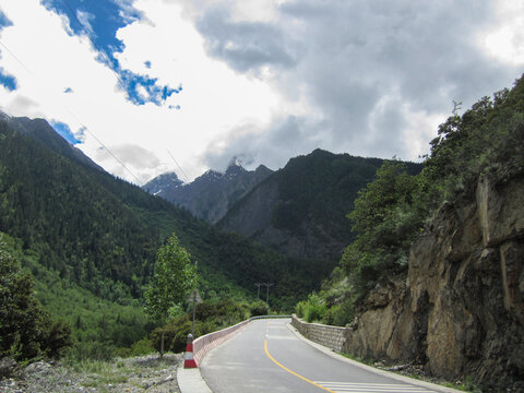 Scenic mountain road with lush green mountains and cloudy sky