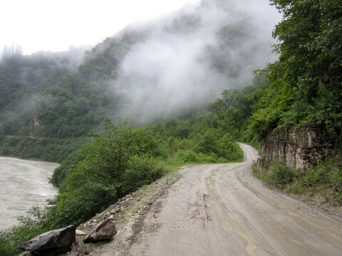 Misty mountain road by the river with lush greenery