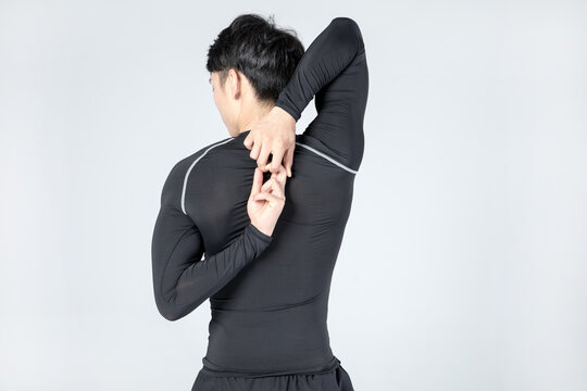 Athletic man stretching shoulders and upper back in studio