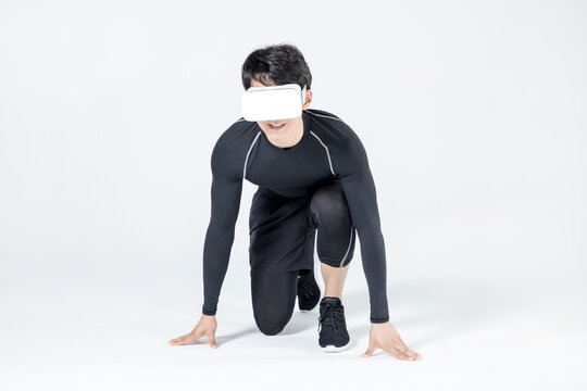 Athletic man wearing virtual reality headset in runner start pose on white background
