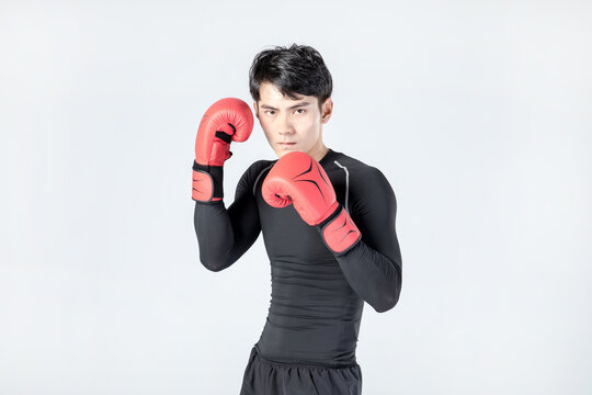 Young man in boxing gloves posing in fighting stance in studio