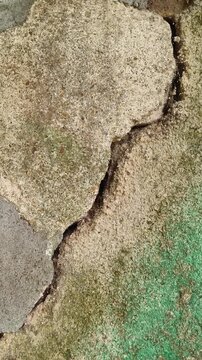 Old weathered cement and stone wall surface with long crack fracture gap damage. Concept of building defect, foundation problems, structural defect, exterior damage and need for repair or inspection.