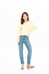 Fototapeta premium Full length young woman posing in yellow sweater and jeans on white background