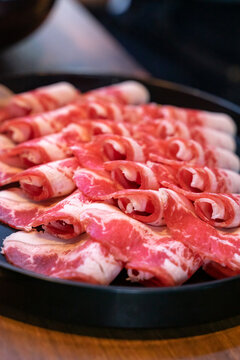 A hotpot meat platter presents thinly sliced beef, pork, and chicken arranged neatly on a serving plate. Close-up compositions emphasize beef marbling, pork color, and the natural fiber patterns of ch