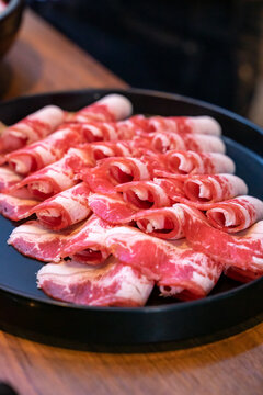 A hotpot meat platter presents thinly sliced beef, pork, and chicken arranged neatly on a serving plate. Close-up compositions emphasize beef marbling, pork color, and the natural fiber patterns of ch