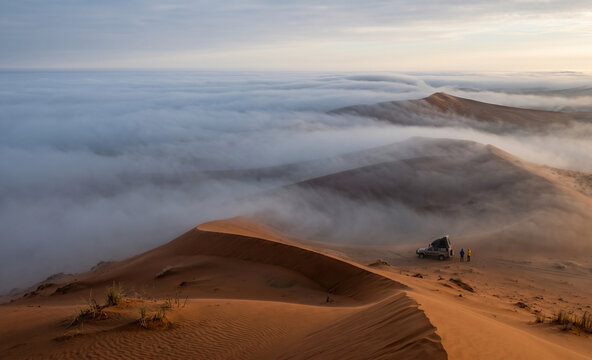  Wide environmental photograph of dense Atlantic coastal fog slowly moving over the Namib Desert dunes