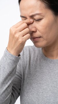 Mature Asian woman pinching nose bridge suffering from sinus pain headache or stress