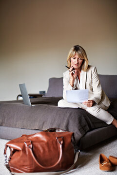 Woman, documents and thinking with finance for travel budget, online flight booking or invoice. Mature, female person or traveler planning business trip with paper or luggage for financial expenses