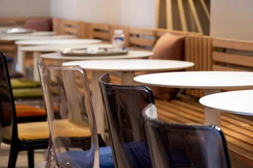 Fotobehang Horeca The dining area features modern white round tables paired with contemporary transparent and coloured acrylic chairs.  © olga46
