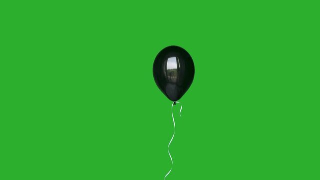Single black helium balloon floating slowly upwards on green screen.