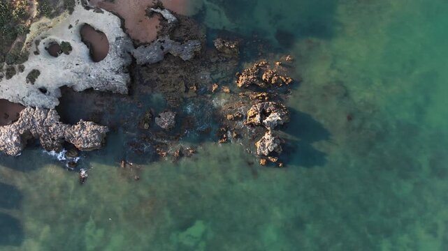 calm rocky coastline aerial view with natural green and brown tones and serene water surface, nature scenes and coastal landscapes, Praia dos Aveiros, Portugal