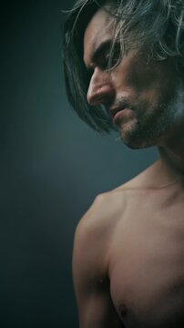 humility suffering Shirtless young man in side-profile portrait with tousled hair and a downward gaze against a dark gradient background, emphasizing sharp jawline and skin texture