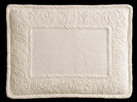 Vintage quilted beige fabric placemat with floral embroidery frame and copy space on black background.