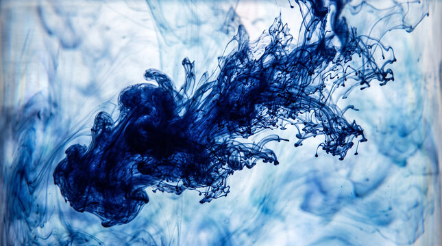 Indigo ink spreading in clear water. Abstract blue liquid cloud flowing in fluid.