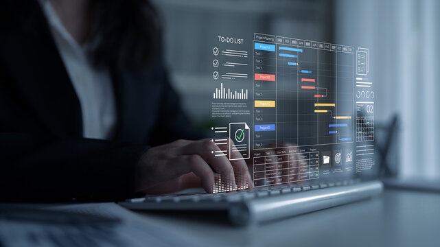 Business professional using futuristic technology to manage tasks and projects with digital interface and graphs on a laptop keyboard in an office setting. Entropy.