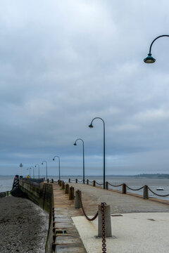 Stone pier Jet&eacute;e de la Fen&ecirc;tre in Cancale, Brittany, France at low tide under cloudy sky.