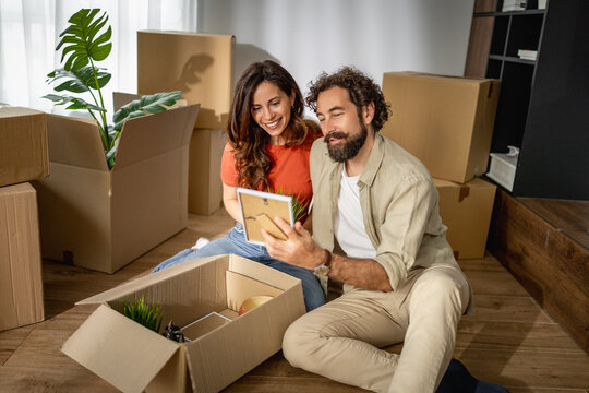 Young couple unpacking boxes and smiling while settling into their new home
