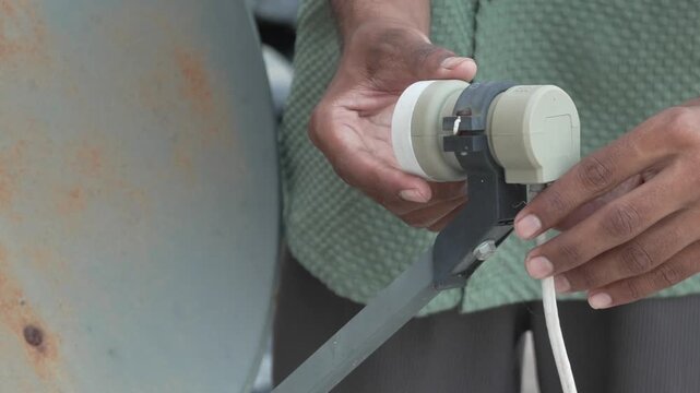 Close-up view of hands holding and setting up the LNB on a satellite dish antenna