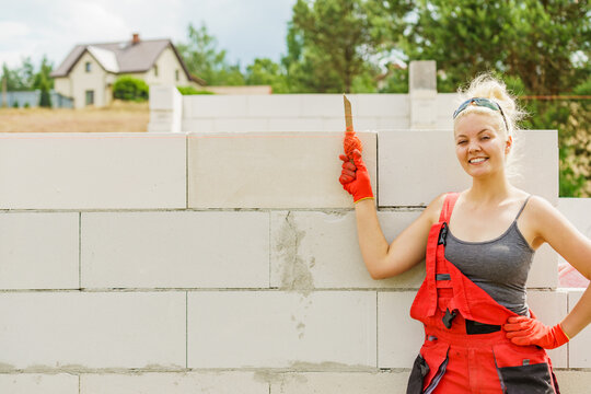 Woman using string as level in wall construction.