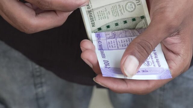 Close-up view of hands holding and counting Indian Rupee currency notes
