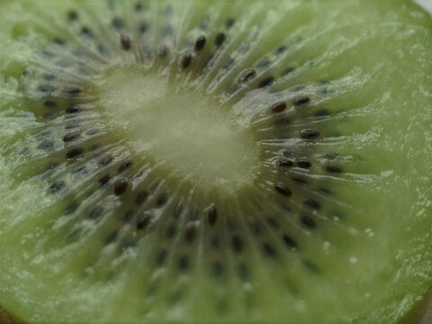 Macro view of juicy sliced green kiwi fruit highlighting intricate seed patterns and pulp texture