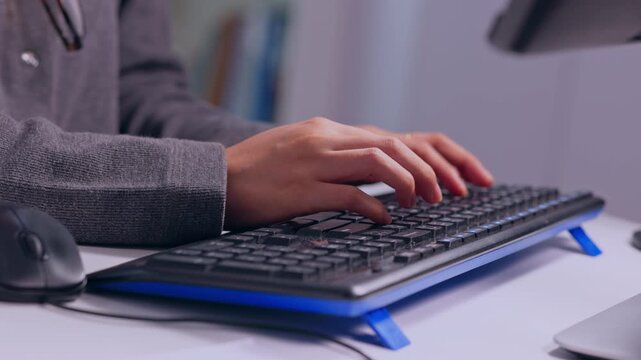 Hands on black keyboard typing at office desk, close up person using computer for work with mouse, monitor, technology, business communication, data entry scene