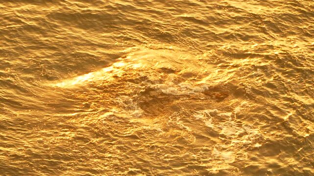 Sunset water golden ripple reflection shimmering abstract background during late evening magic hour.