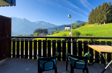 Fototapeta premium cozy wooden balcony with comfortable lounge chair overlooking scenic green mountains